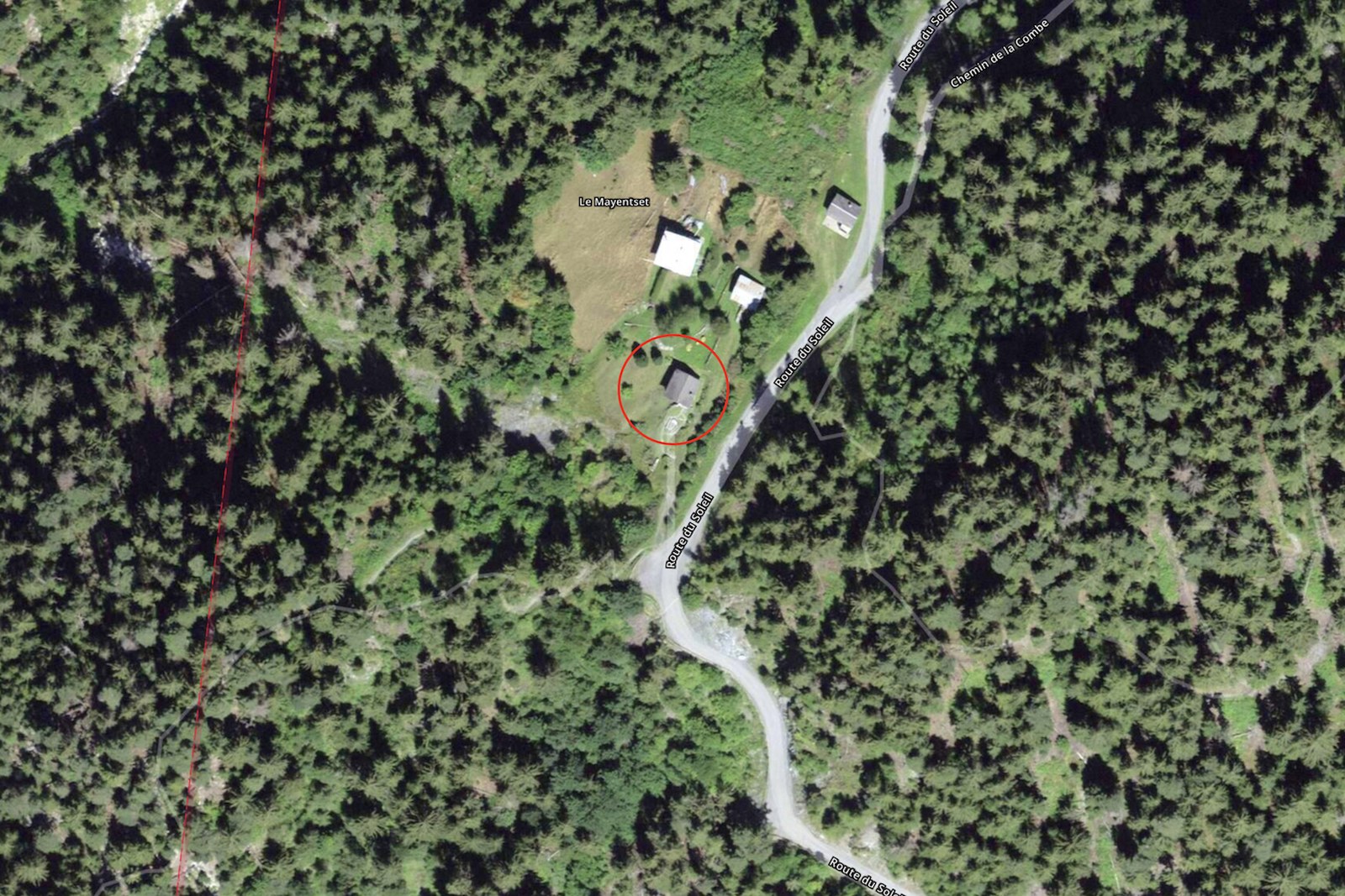 Vue aérienne du Mayentset : le chalet cerclé de rouge au bord de la Route du Soleil, forêt de sapins tout autour.